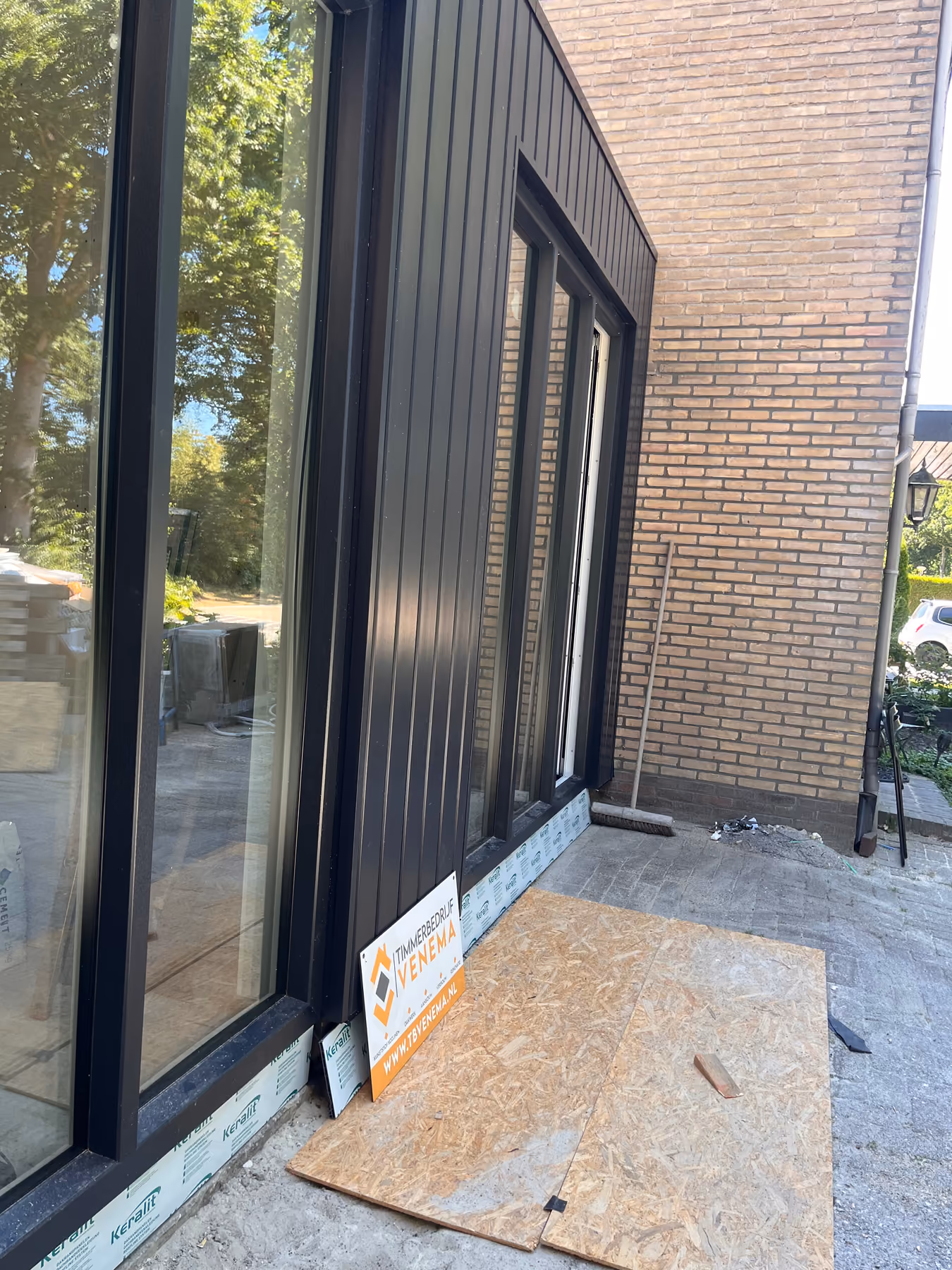 Detail van donkere gevelbekleding die aansluit op de bestaande baksteen gevel