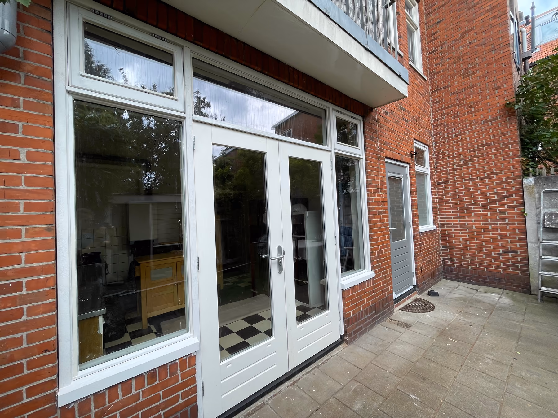 Witte openslaande tuindeuren met zijramen en bovenlichten in een bakstenen achtergevel