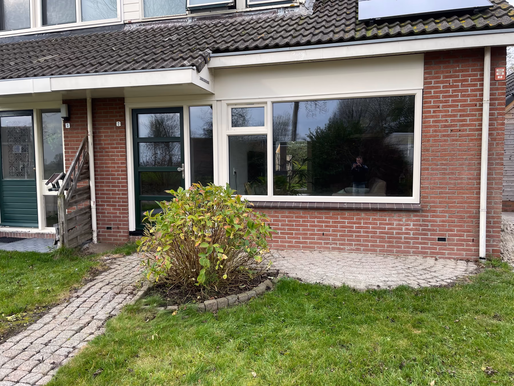 Voorgevel met nieuw breed raam en donkergroene voordeur