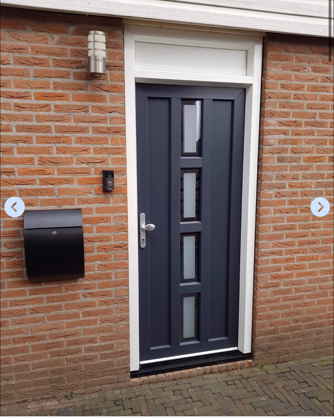Nieuwe antracietkleurige voordeur met glasstroken en wit kozijn in bakstenen gevel