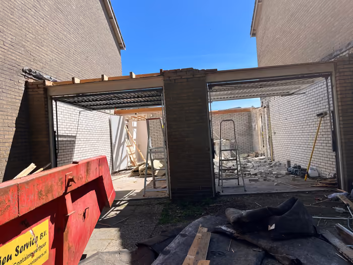 Twee garageopeningen met stalen lateien en houten dakrand tijdens de sloopfase
