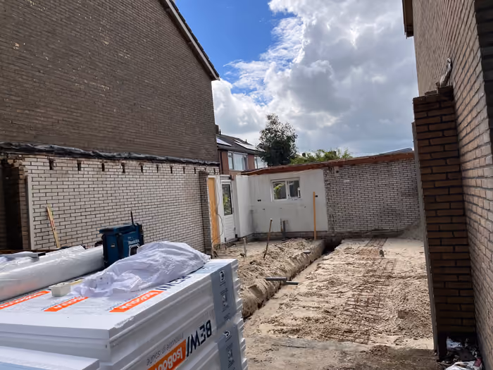 Zandbed met funderingssleuf en wapening, stapel isolatieplaten op de voorgrond