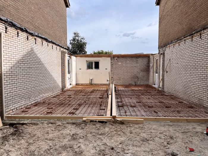 Vloerwapening en houten bekistingsrand van de nieuwe aanbouw voor het storten