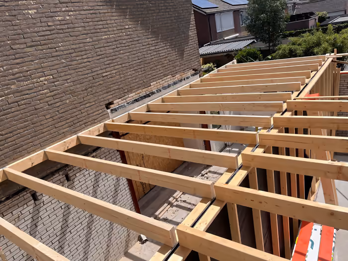Houten dakbalken van de aanbouw tegen de bestaande gevel, dak nog open