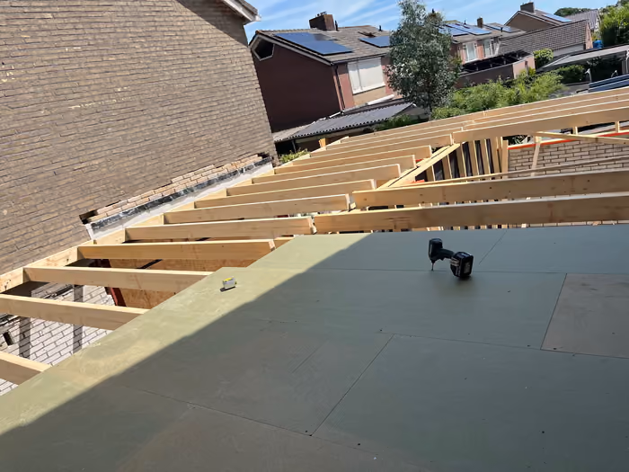 Dakplaten gelegd op de houten balklaag, accugereedschap staat op het dak