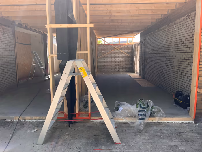 Gestorte vloer in de aanbouw met houten wandregels en een trapladder