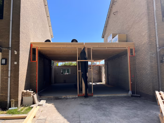 Houtskelet van de dubbele aanbouw tussen twee woningen, dak al dichtgelegd