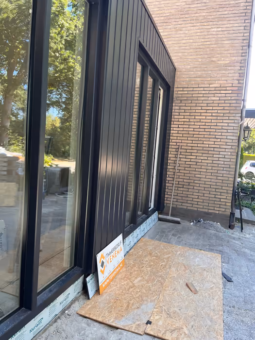 Detail van donkere gevelbekleding die aansluit op de bestaande baksteen gevel