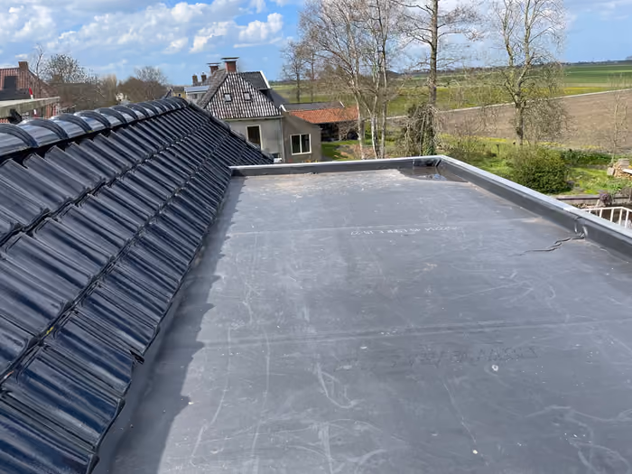 Plat dak van dakkapel met zwarte dakbedekking en zinken randafwerking