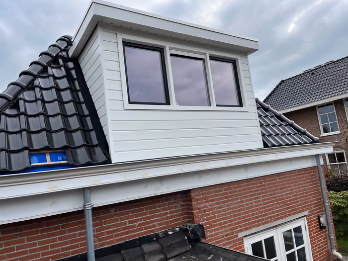 Witte dakkapel met drie ramen op een nieuw antraciet pannendak