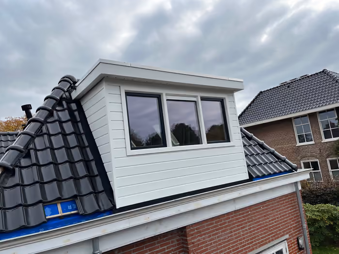 Zijaanzicht van witte dakkapel met drie ramen op zwart pannendak