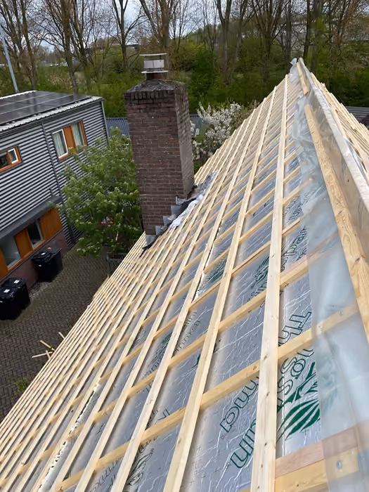 Dakvlak met isolatieplaten en nieuw tengel- en panlattenwerk rond een schoorsteen