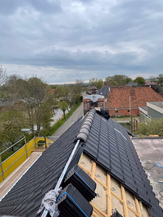 Nok met nieuwe donkere dakpannen, deel van het dakvlak nog onbedekt