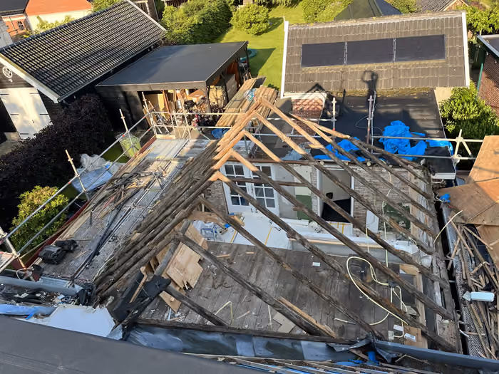 Bovenaanzicht van een woning met kaalgemaakt dak en zichtbare spanten