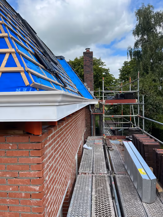 Witte goot en boeiboord onder een dakvlak met blauwe folie en panlatten