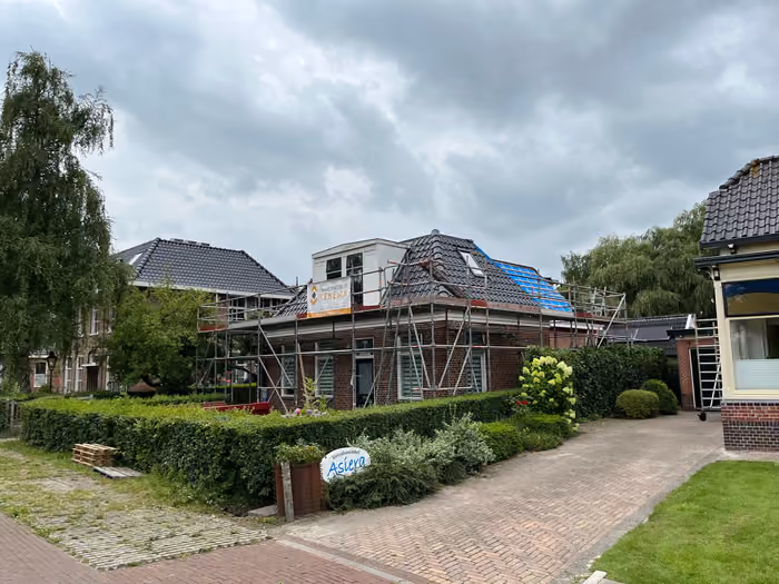 Woning in de steigers met deels gelegde nieuwe dakpannen en witte dakkapel