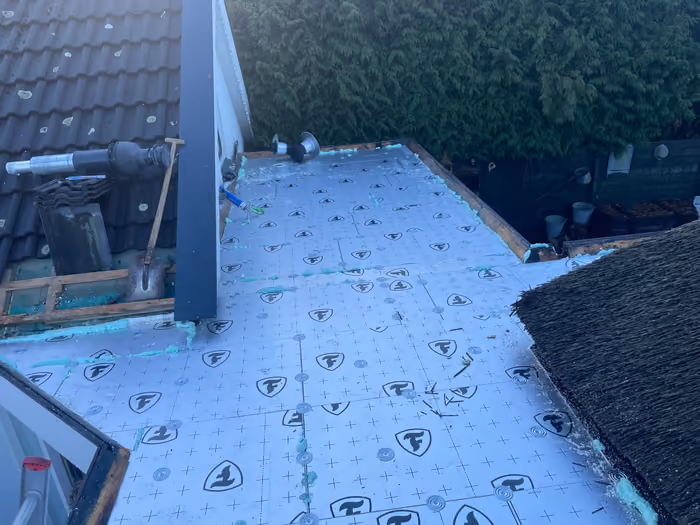 Isolatieplaten met purschuim op een plat dak, ventilatiepijpen en rieten dak