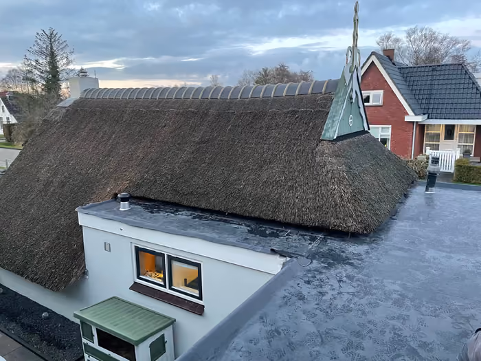 Woning met rieten dak en afgewerkt plat dak in avondlicht