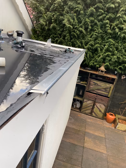 Aluminium daktrim langs de rand van een plat dak, met accuboormachines