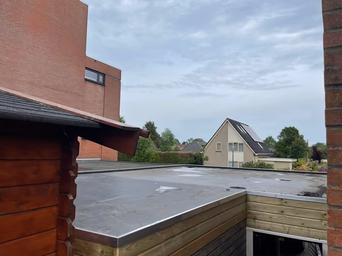 Afgewerkt plat dak met zwarte dakbedekking en metalen daktrim langs de rand