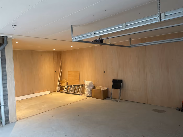 Garage-interieur met plaatmateriaal op wanden en plafond en rails van een sectionaaldeur