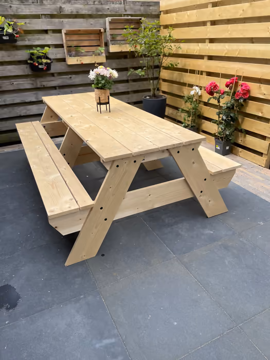 Nieuwe houten picknicktafel met vaste banken op een grijs betegeld terras