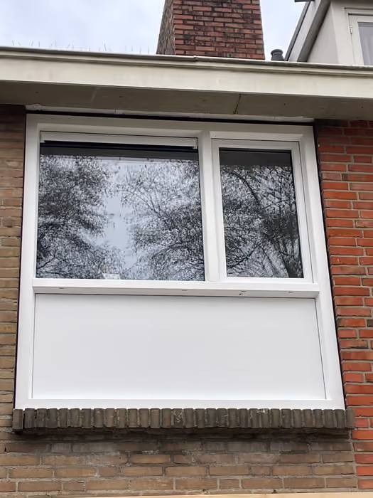 Nieuw wit kozijn met bovenlichten en dicht paneel onder de ramen