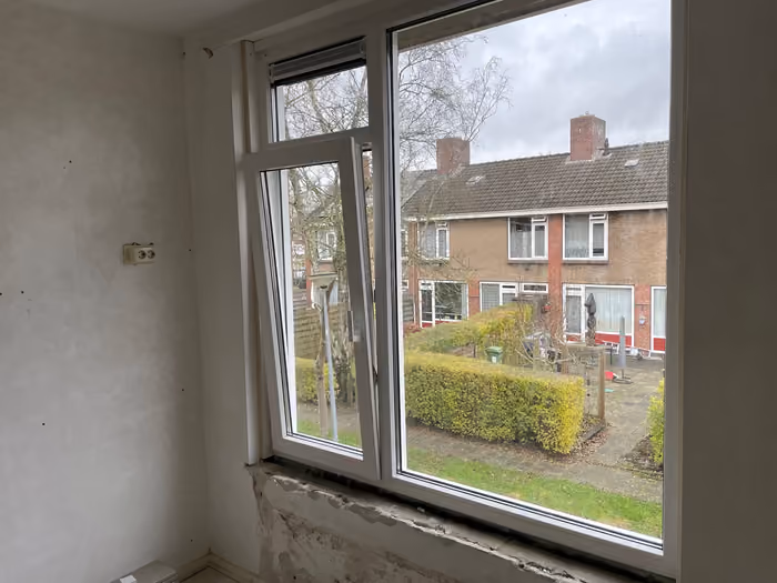 Nieuw wit kozijn met draaikiepraam, binnenmuur en vensterbank nog onafgewerkt