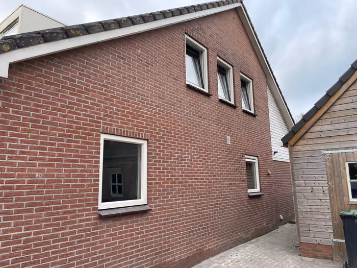 Zijgevel met nieuwe witte kozijnen en drie kleine ramen onder de kap