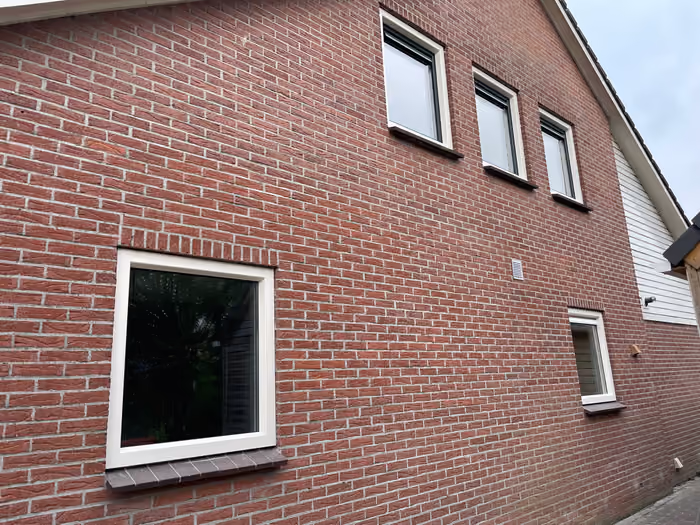 Zijgevel met nieuwe witte kozijnen en ramen onder de puntgevel