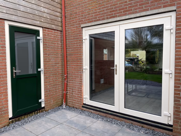 Witte dubbele tuindeuren en groene achterdeur in bakstenen achtergevel