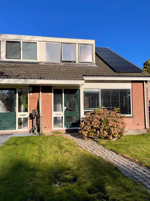 Rijtjeswoning met dakkapel, groene voordeuren en witte kozijnen in de voorgevel