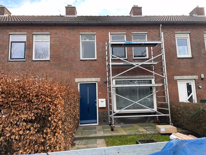 Rolsteiger voor de voorgevel van een rijtjeswoning met blauwe voordeur