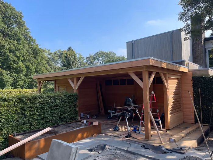 Houten overkapping met plat dak in aanbouw onder blauwe lucht