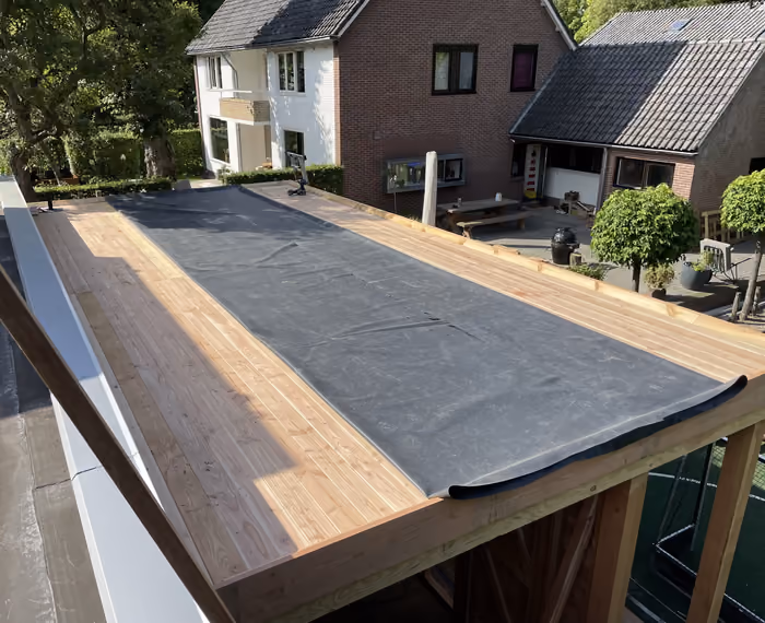 Plat dak van een tuinschuur met EPDM-folie half uitgerold over de dakbeschieting