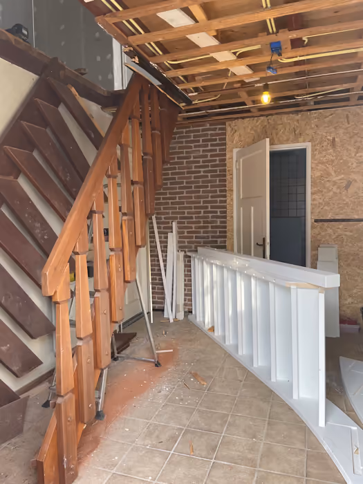 Oude houten trap met nieuwe witte balustrade, plafond gestript tot de balken