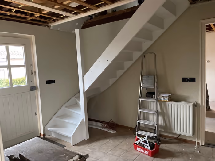 Nieuwe witte trap in de hal, plafond gestript tot de balklaag