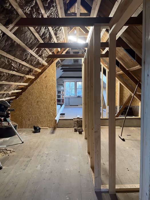 Zolder met oude dakspanten en isolatie, nieuw regelwerk en doorkijk naar kamer