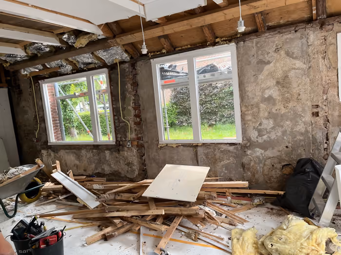 Gestripte kamer met kale muren, nieuwe kozijnen en sloophout op de vloer