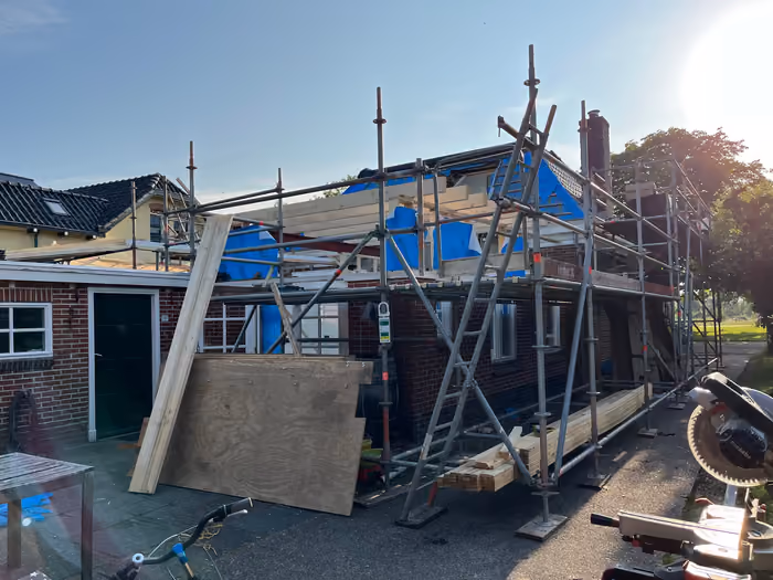 Woning met steiger, dak deels geopend en blauwe folie op de gevel