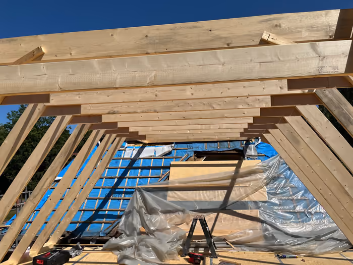 Nieuwe houten spanten en gordingen van de kapconstructie tegen een blauwe lucht