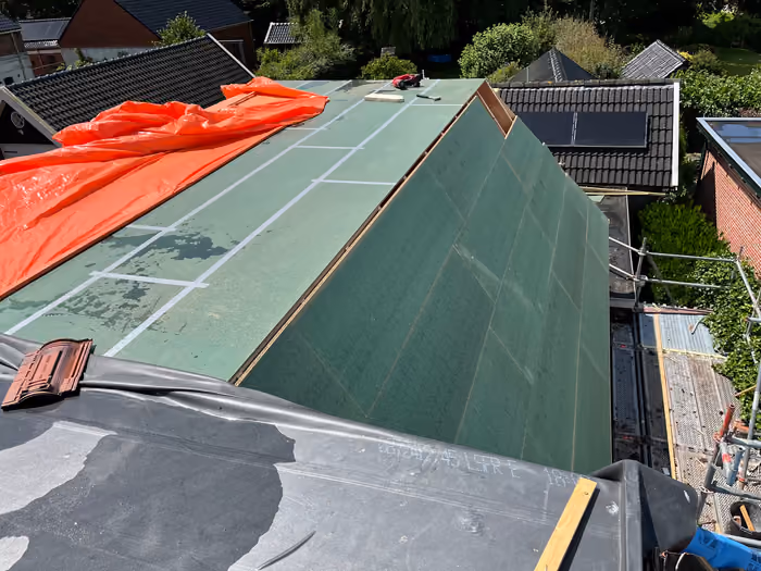 Beide dakvlakken dichtgezet met groene dakbeschotplaten en een oranje dekzeil