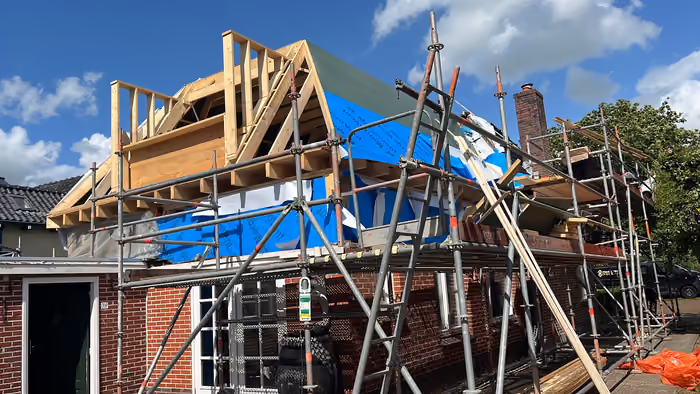 Woning met steiger, nieuwe houten kapconstructie en blauwe folie op de gevel