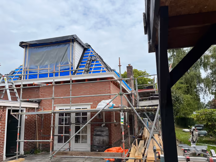 Woning met steiger, dakkapel in aanbouw en blauwe folie op het dakvlak