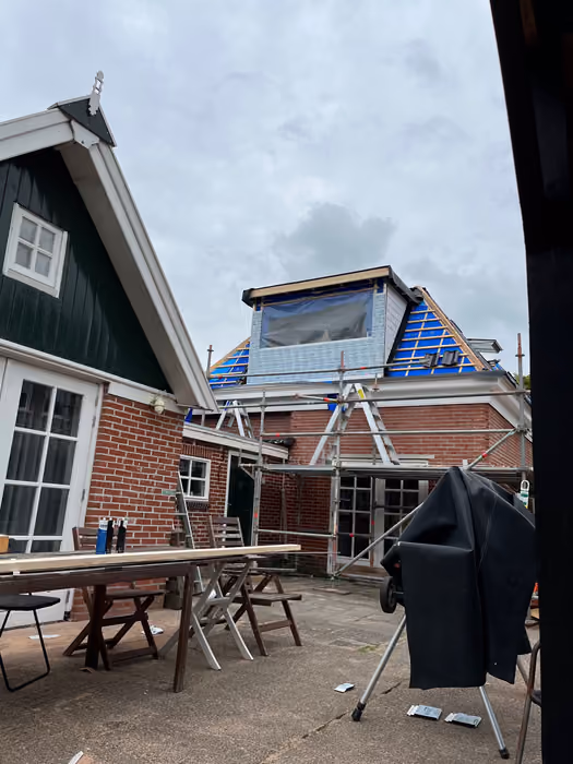 Terras met tuinmeubels en daarachter huis met steiger en dakkapel