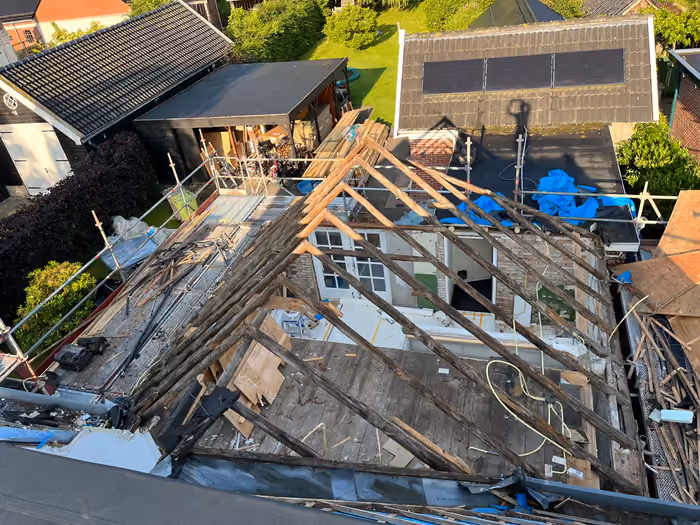 Bovenaanzicht van gestript dak met houten spanten en sloopmateriaal