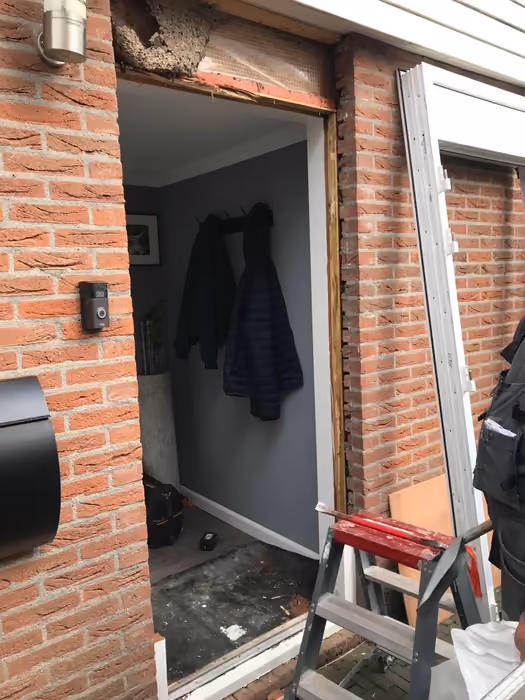 Lege deuropening met gestript metselwerk en nieuw kozijn klaar voor montage