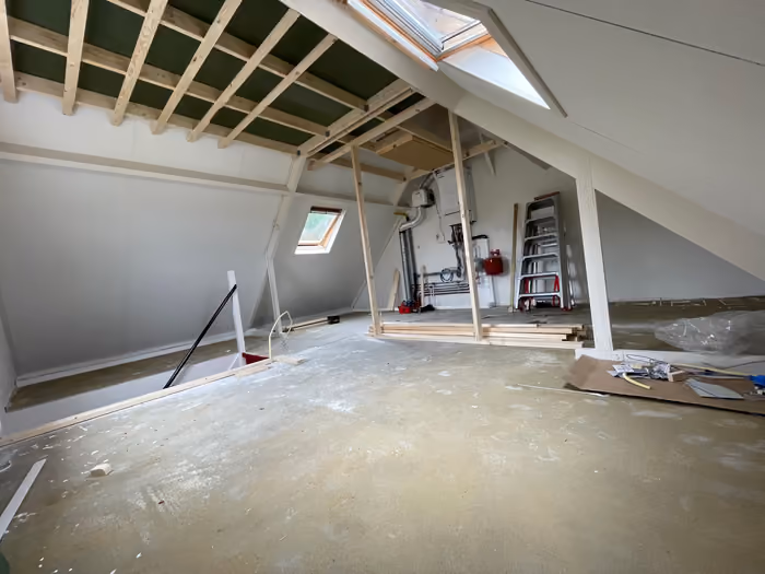 Zolder met afgewerkte schuine wanden, dakramen en nieuw houten regelwerk